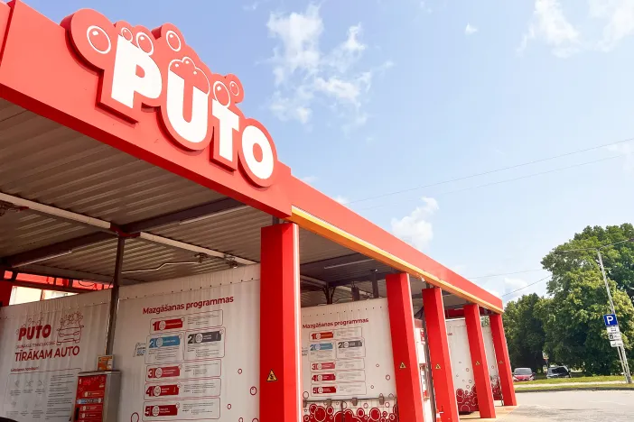 Sarkanas automazgātuves ēka ar zilu debesu fonu.