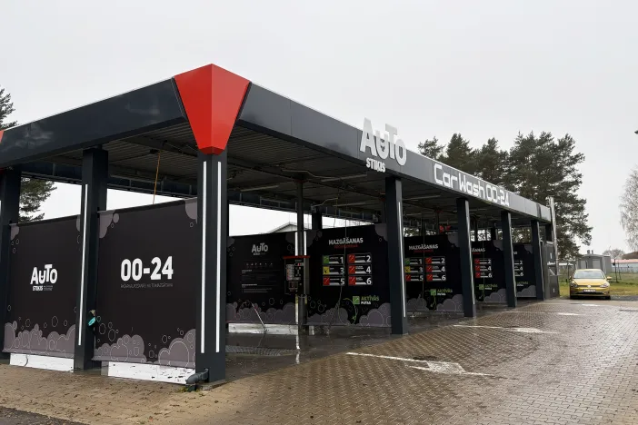 Tum&scaron;a automazgātava ar norādēm, pelēkas debesis.