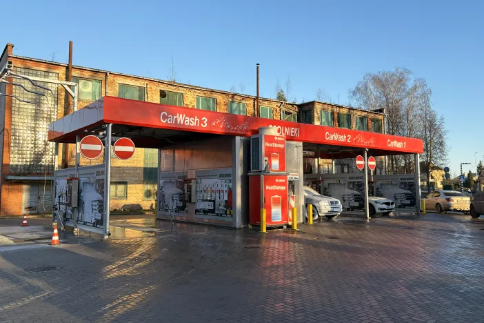 Sarkana automazgātava ar divām mazgā&scaron;anas zonām, saulainā dienā.