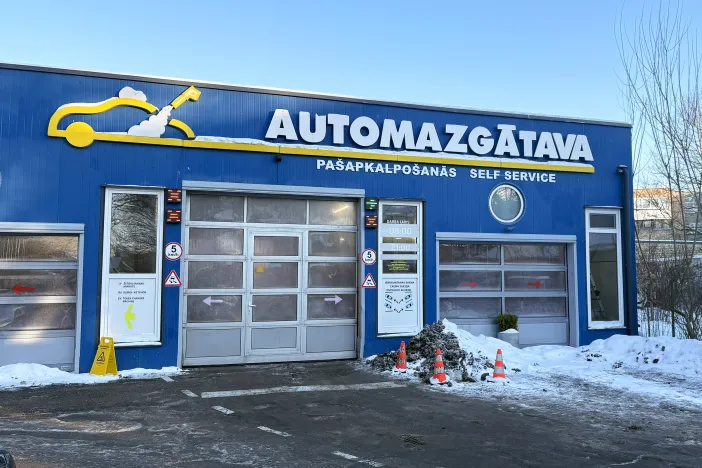 Automa&scaron;īnas mazgātava ar zilu fasādi un slēgtām garāžas durvīm.