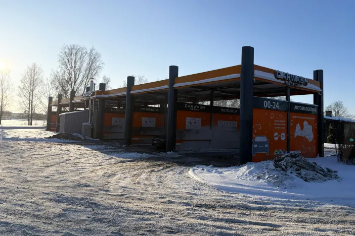 Pa&scaron;apkalpo&scaron;anās automazgātava sniegotā ainavā, oranži un melni toņi.