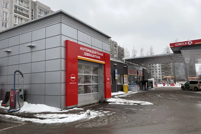 Automa&scaron;īnu mazgātava ar sarkanu fasādi sniegotā pilsētā.