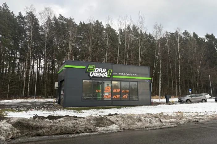 Pelēka automazgātava meža malā, ziemas ainava.