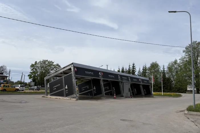 Automa&scaron;īnu mazgātava ar melnu nojumīti, pasteļzilām debesīm fonā.