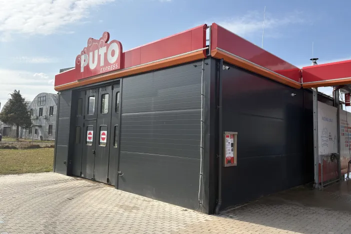 Automa&scaron;īnu mazgātuve ar sarkanu jumtu saulainā dienā.