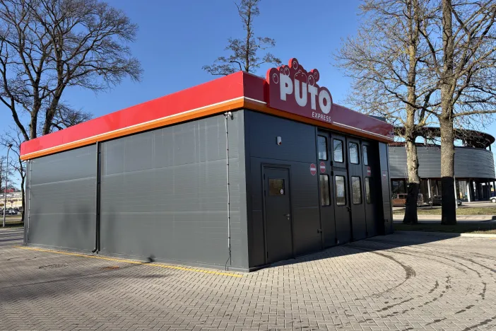 Pelēka automazgātava ar sarkanu jumta noformējumu.