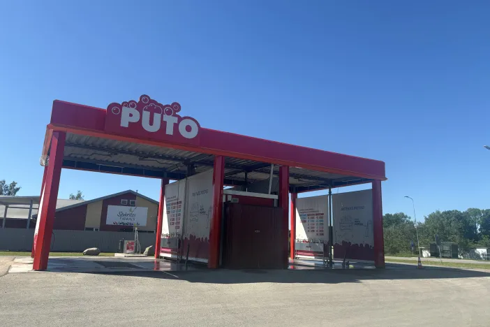 Automa&scaron;īnu mazgātava ar sarkanu jumtu saulainā dienā.