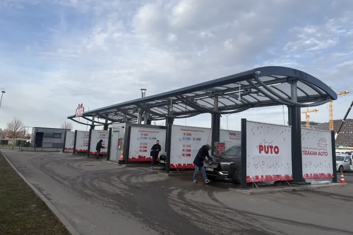 Automa&scaron;īnu mazgātava ar trim mazgā&scaron;anas stacijām, cilvēki tīra savas automa&scaron;īnas.
