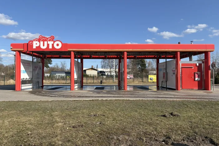 Sarkanā automazgātava saulainā dienā ar skaidrām debesīm.